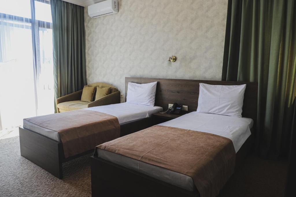 Mūsdienīgs viesnīcas numurs ar divām atsevišķām gultām, dīvānu un lieliem logiem, kas nodrošina dabisko apgaismojumu. Interjerā ir zaļi aizkari un neitrālas krāsas dekors.