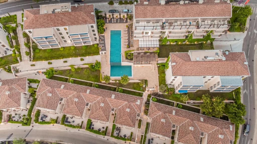 Apskatāma modernu dzīvojamā kompleksa gaisa skats ar peldbaseinu un zaļajiem apstādījumiem. Apkārt esošās ēkas veido harmonisku un pievilcīgu vidi.