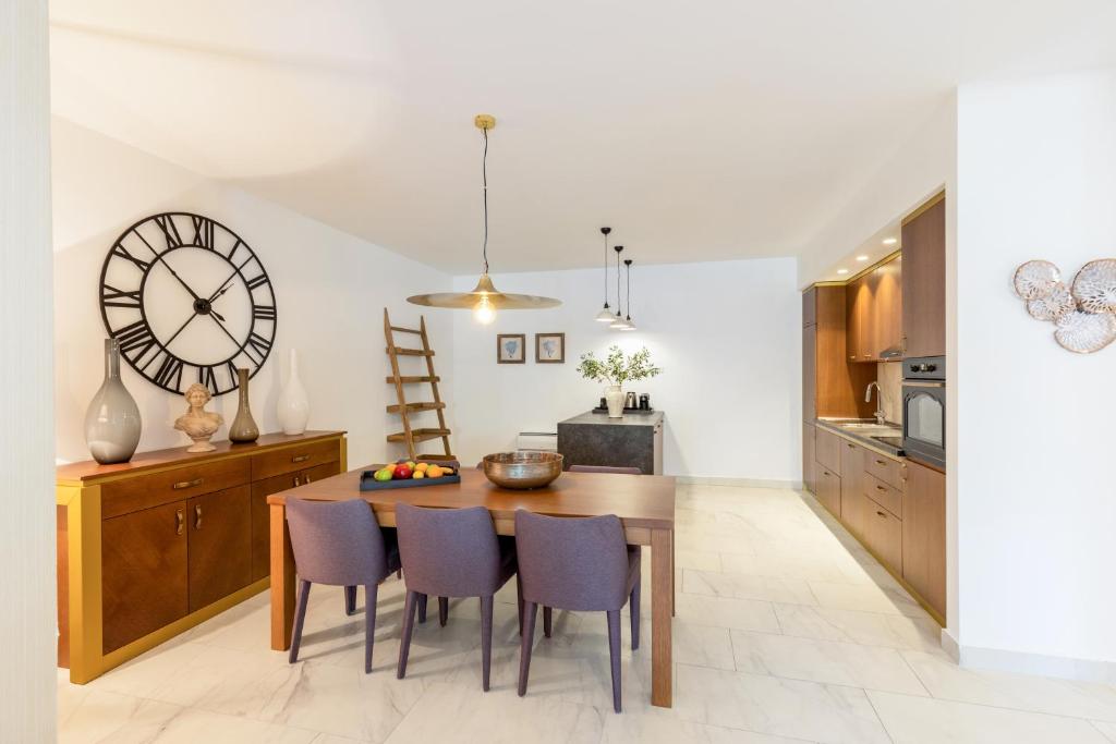 Mūsdienīga virtuve ar ēdamgaldu, senu pulksteni un stilīgiem dekoriem. Svaigas krāsas un eleganta mēbele rada mājīgu atmosfēru.