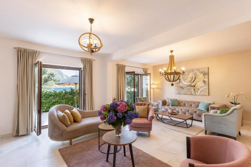 Elegants viesistabas interjers ar mūsdienīgu apgaismojumu, krāsainām mēbelēm un ziedu kompozīciju. Lielas logu durvis nodrošina dabisko apgaismojumu un skatu uz dārzu.