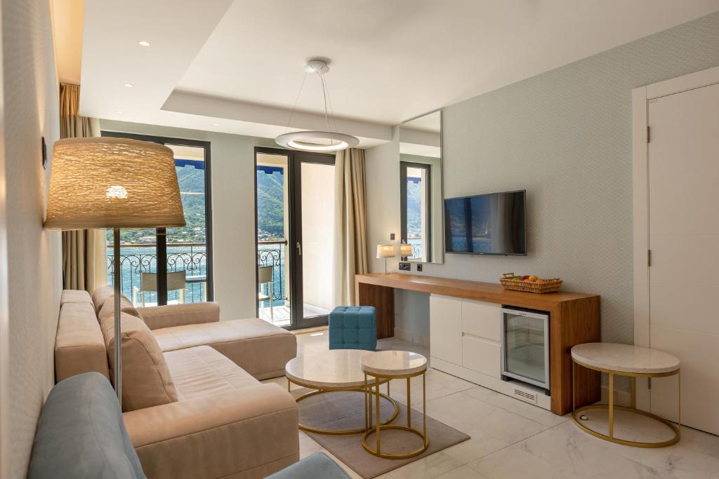 Mūsdienīgs viesnīcas numurs ar plašu viesistabu, elegantām mēbelēm un balkonu, no kura paveras skats uz kalniem un ūdeni. Gaišs interjers ar dabiskiem toņiem un modernām tehnoloģijām.