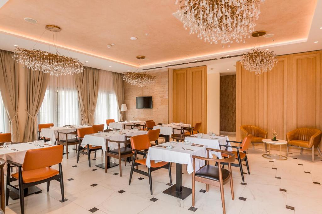 Mūsdienīgs restorāns ar elegantu interjeru, kurā ir baltas galdautas un stilīgas gaismas ķermeņi. Izcila atmosfēra, kas aicina pievērsties gardām maltītēm.