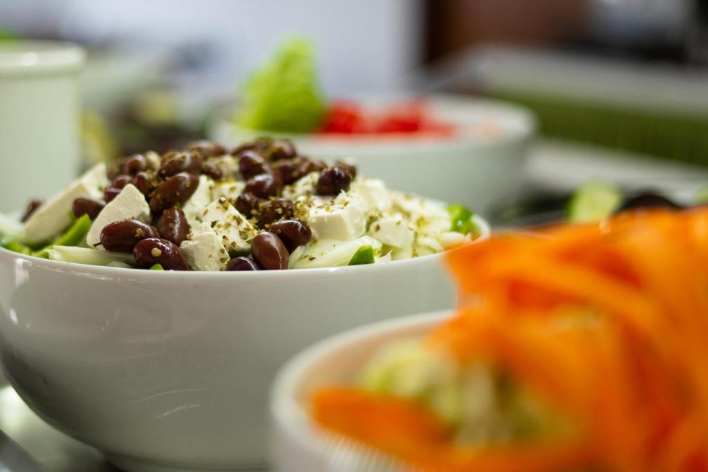 Svaigas salātu bļoda ar melnajām pupiņām un fetas sieru, dekorēta ar zaļumiem. Fons satur dažādas dārzeņu sastāvdaļas.