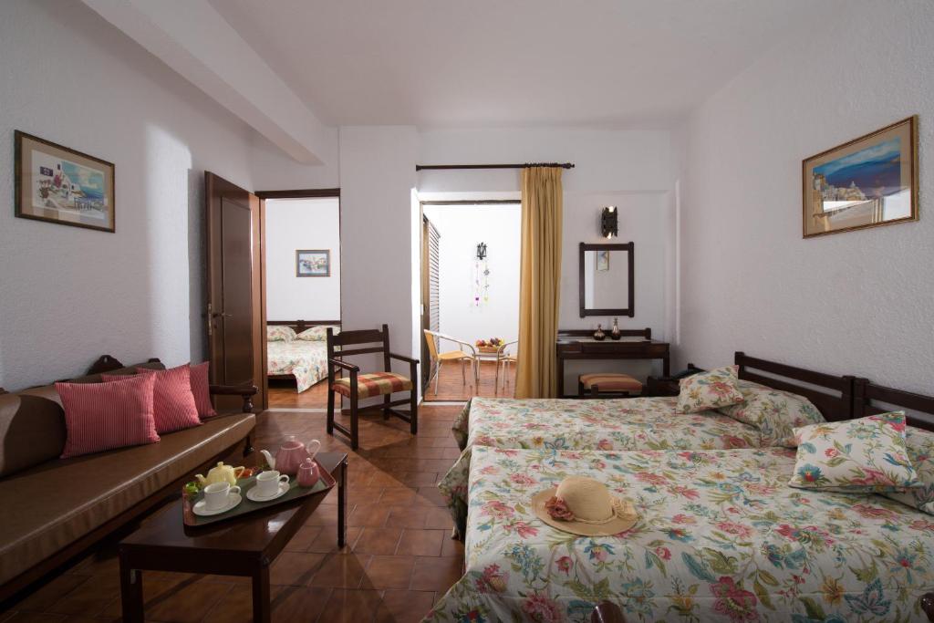 Mūsdienīga viesnīcas istaba ar divām gultām, dīvānu un galdiņu, apkalpotu ar tējas komplektu. Interjers ir gaišs, ar ziedu rakstiem un mākslas darbiem uz sienām.