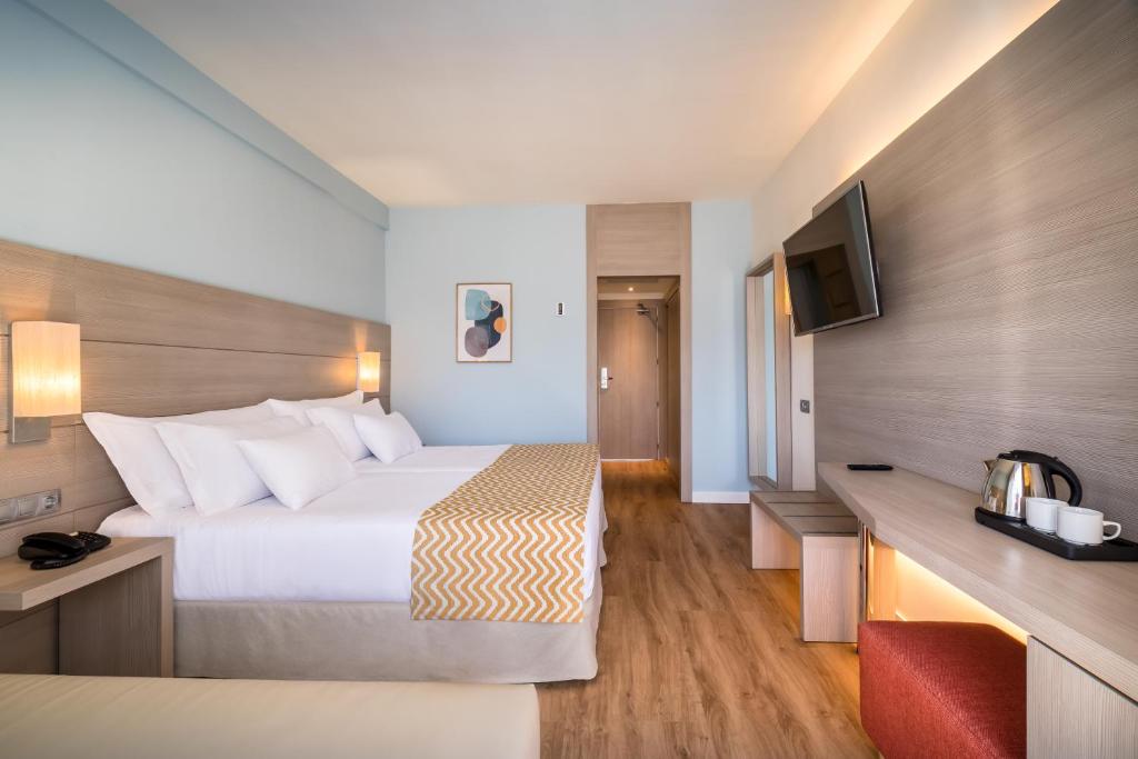 Mūsdienīgs viesnīcas numurs ar divām gultām, koka grīdām un minimālistisku interjeru. Numurā ir televizors, galda virsma un tēja vai kafija.