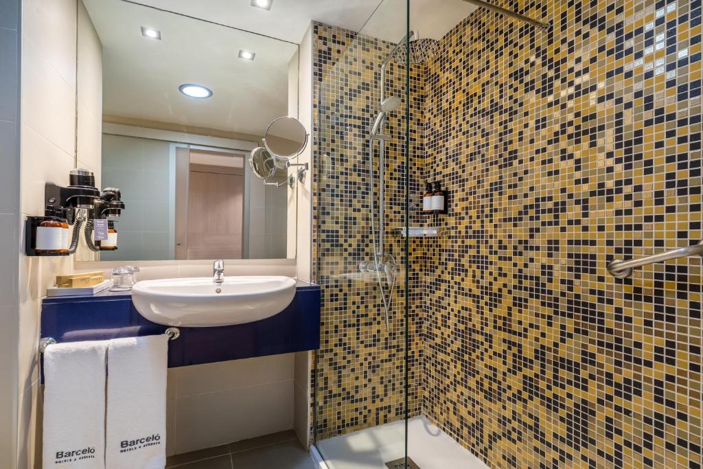 Mūsdienīga vannas istaba ar stikla dušu un mozaīku sienām. Uzsvars uz eleganci un komfortu, ar stilīgu izlietni un higiēnas piederumiem.