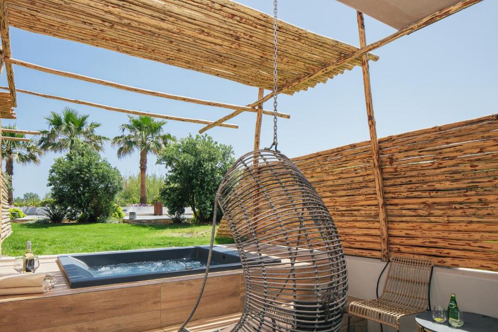 Atpūtas zona ar siltu burbuļvannu, šūpuļkrēslu un zaļiem palmām fonā, ideāla atpūtai un relaksācijai.