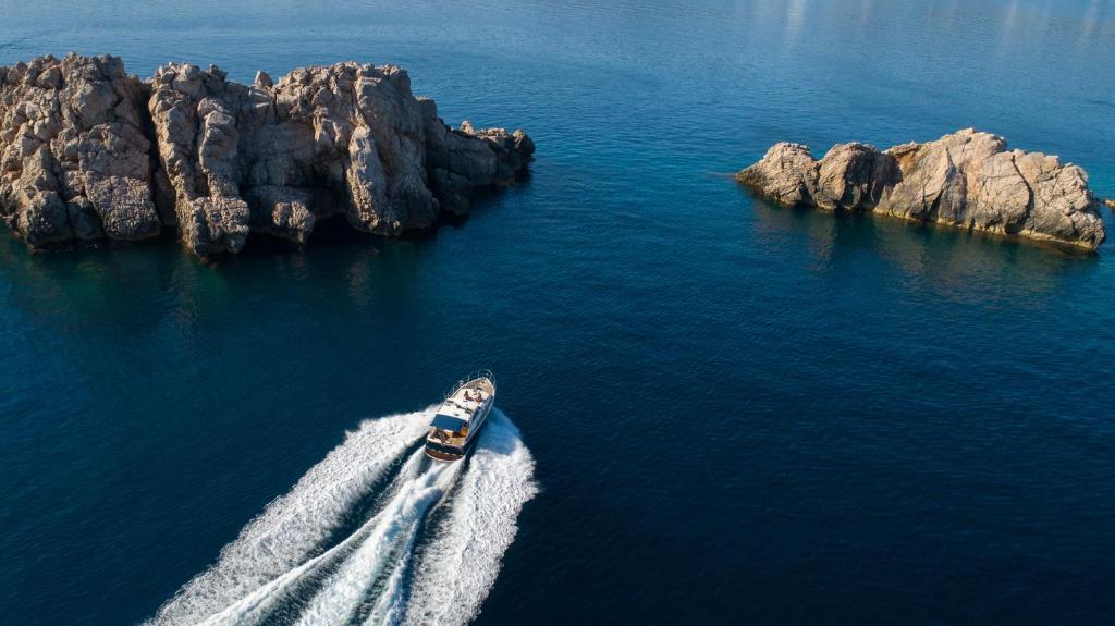 Kuģis pārvietojas pa mierīgu jūru, tuvāk akmeņainiem krastiem. Ūdens ir dzidrs, un akmeņi ir redzami virs ūdens virsmas.