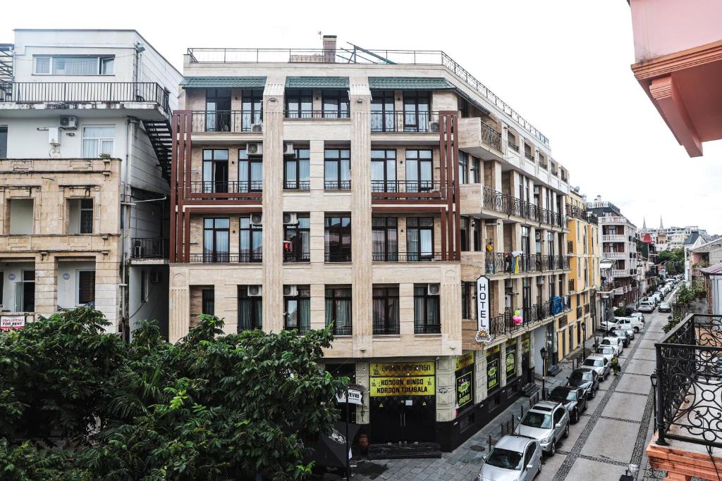 Daudzdzīvokļu ēka ar modernu arhitektūru un balkoniem, redzama ielas perspektīvā. Apkārtējā teritorija ir apzaļumota un ietver stāvvietu automašīnām.