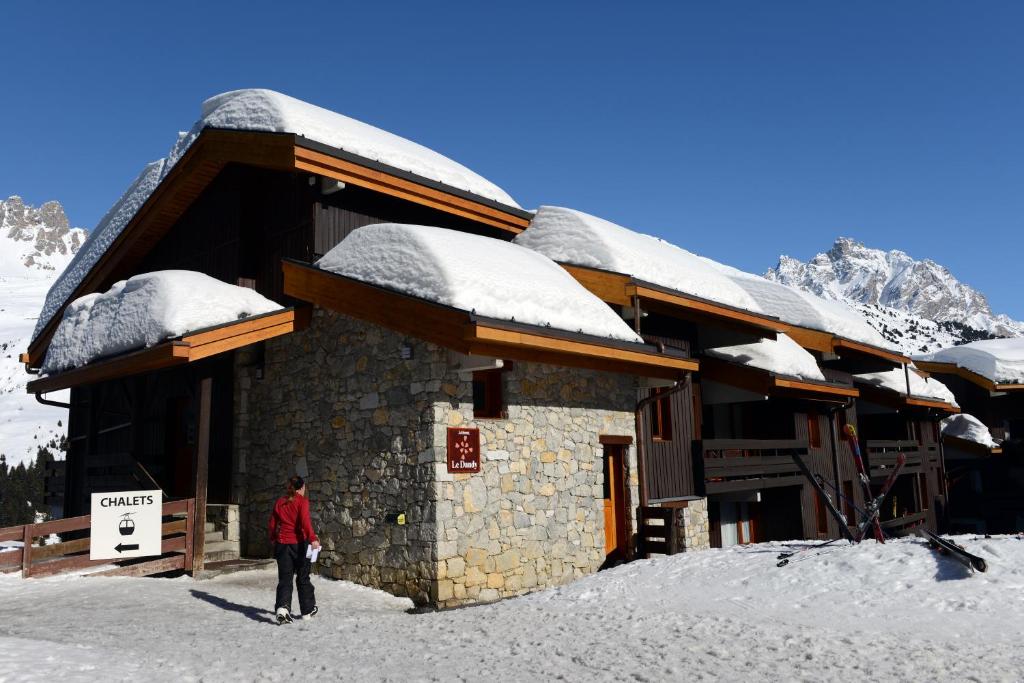 Alpu mājiņas ar sniega segumu un kalnu ainavu, kas rada ziemas atpūtas atmosfēru. Ideāla vieta slēpošanai un relaksācijai.