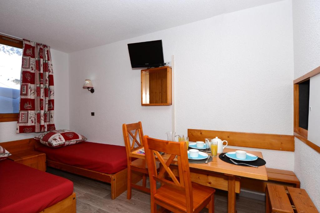 Maza, omulīga viesnīcas istaba ar divām gultām, koka mēbelēm un ēdamgaldu, uz kura ir brokastu trauki. Logā redzama sniega ainava, un istabā ir televizors.