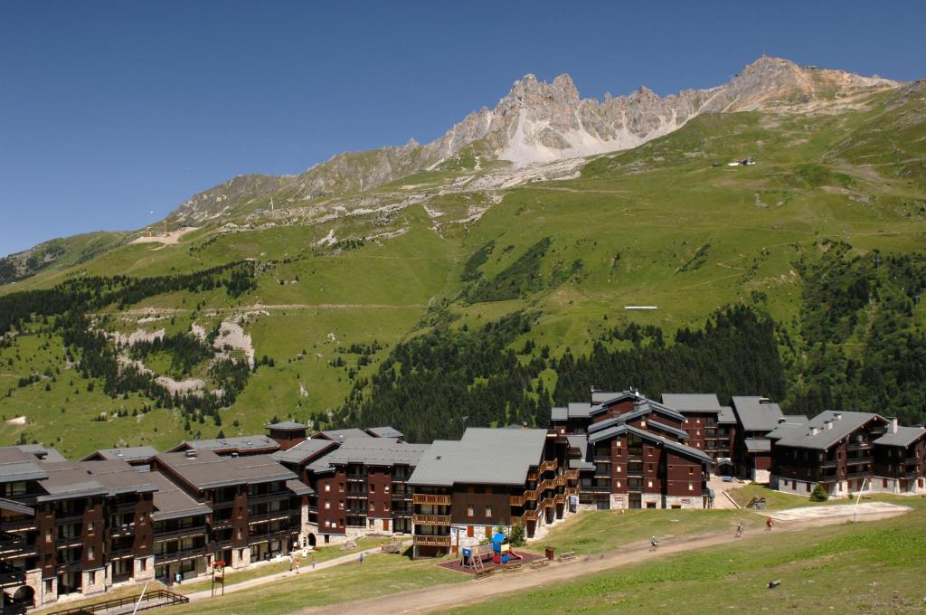 Kalnu naktsmītnes ainava ar zaļiem pakalniem un kalnu virsotnēm. Ideāla vieta atpūtai un piedzīvojumiem dabā.