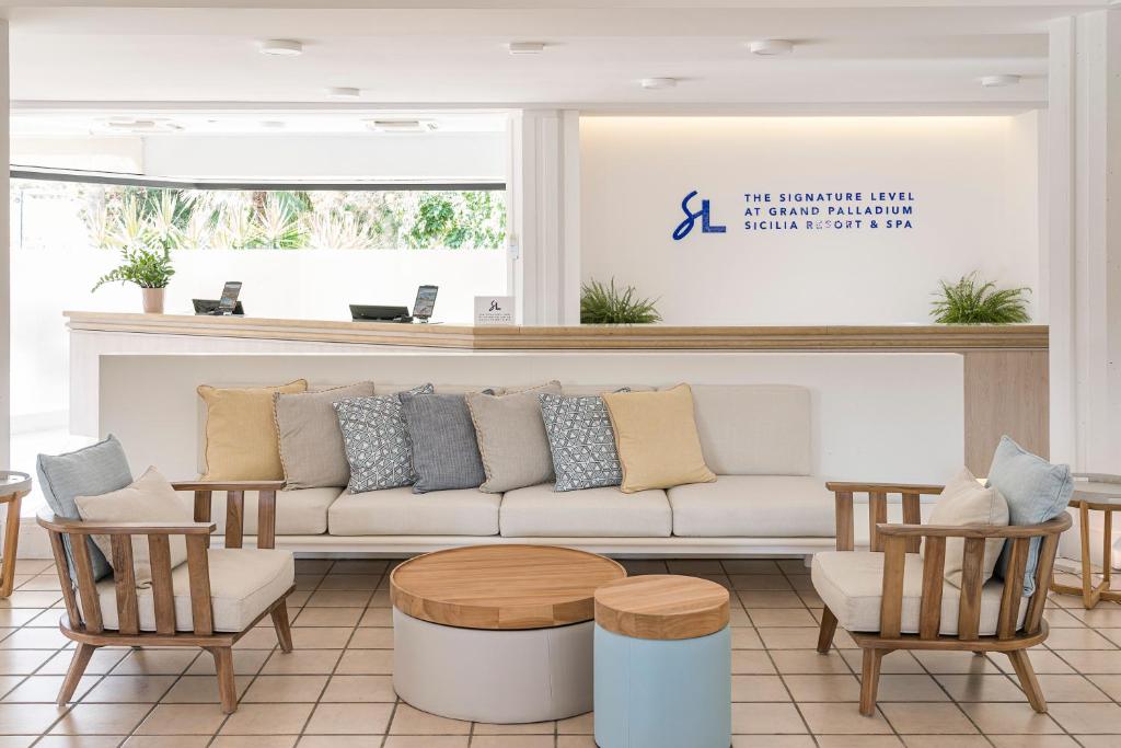 Mūsdienīgs viesnīcas reģistratūras interjers ar ērtu dīvānu un krēsliem, kā arī zīmolu "The Signature Level" logo. Gaisīgs un viesmīlīgs atmosfēra.