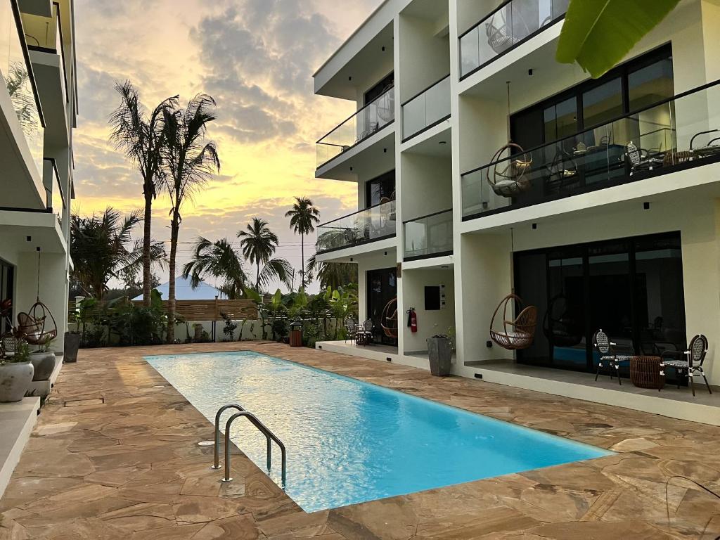 TOA Hotel & Spa baseins pie saulrieta ar palmu fonu.