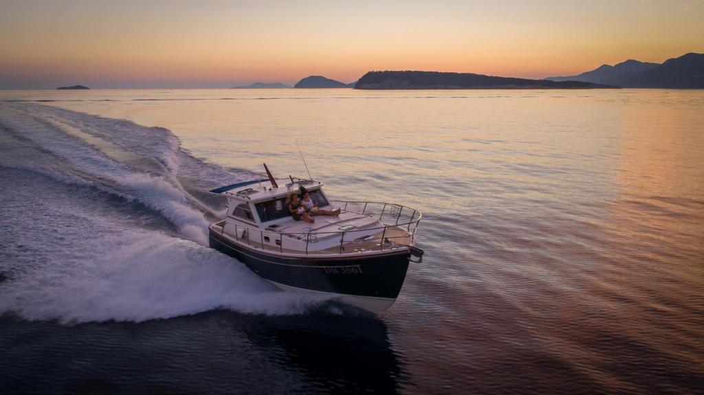 Jahtas brauciens pie saulrieta ar mierīgu ūdeni, apkārt kalni un salas.