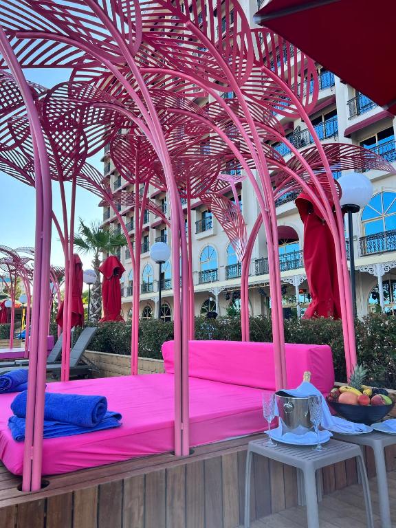 Rozā atpūtas zona pie Megasaray Westbeach Antalya ar dīvānu un augļiem.