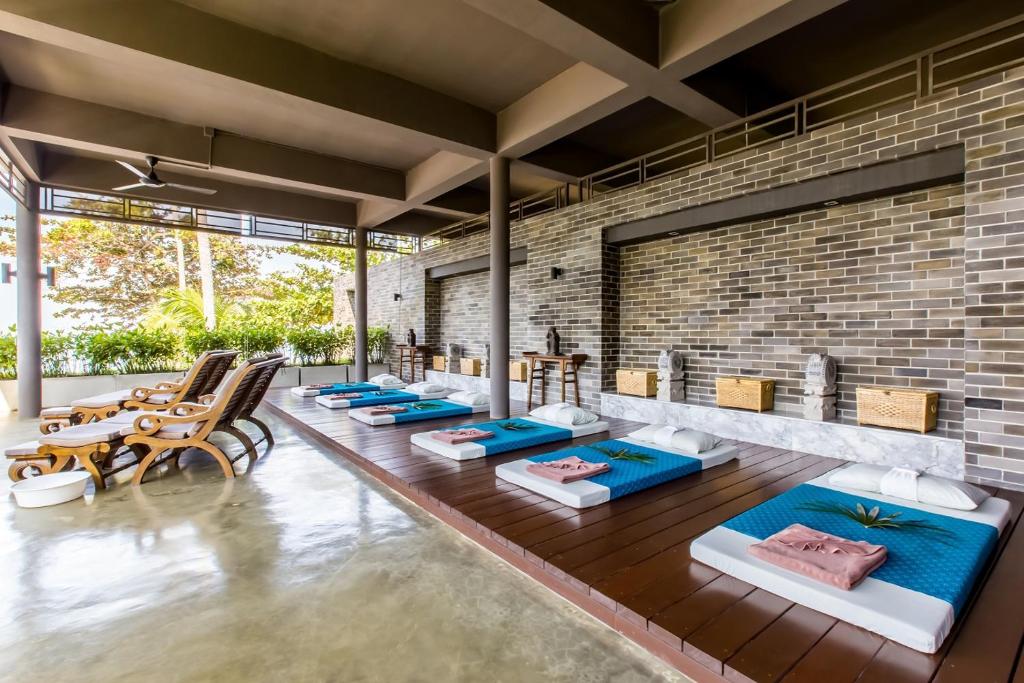 Mūsdienīgs spa interjers ar masāžas gultām un atpūtas krēsliem, kas nodrošina relaksējošu atmosfēru. Telpa ir gaiša un atvērta, ar skatu uz dabu.