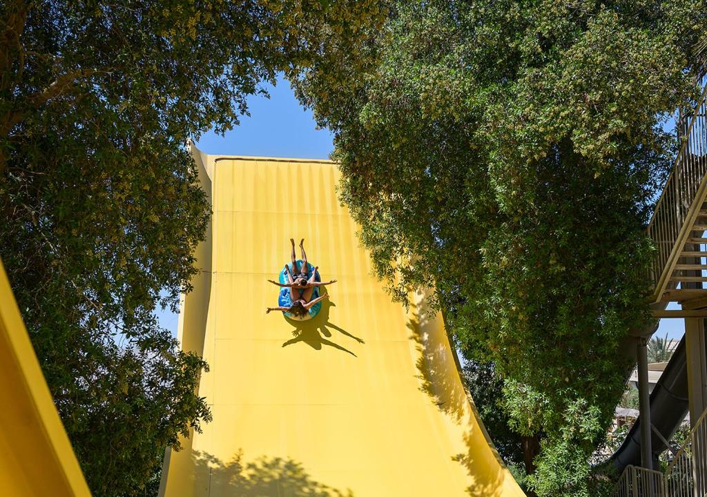 Divi apmeklētāji izbauda atrakciju uz dzeltenā ūdens slidkalniņa Sindbad Club