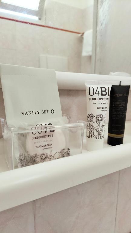 Vannas istabas preču komplekts, kas ietver dārzeņu ziepes, ķermeņa losjonu un argana eļļu, sakārtots uz plaukta.