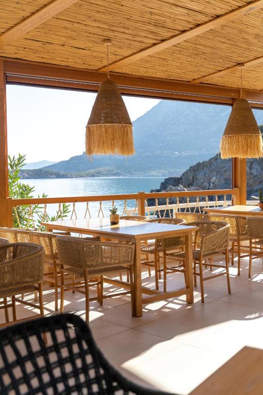 Elegants restorāns ar skatu uz jūru, kur koka mēbeles un pītās krēsli rada relaksējošu atmosfēru. Gaismas plūst caur atvērtajām terasēm, piedāvājot skaistus dabas skatus.