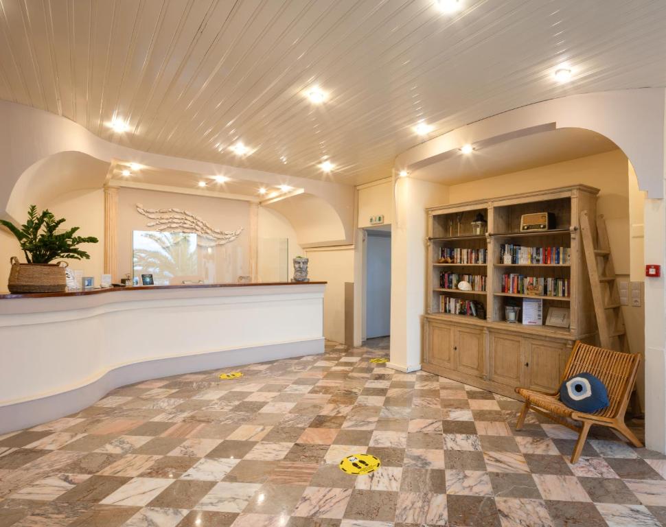 Mūsdienīgs viesnīcas reģistratūras interjers ar marmora grīdu, koka grāmatu plauktu un augu dekorācijām. Gaismas un telpas dizains rada viesmīlīgu atmosfēru.