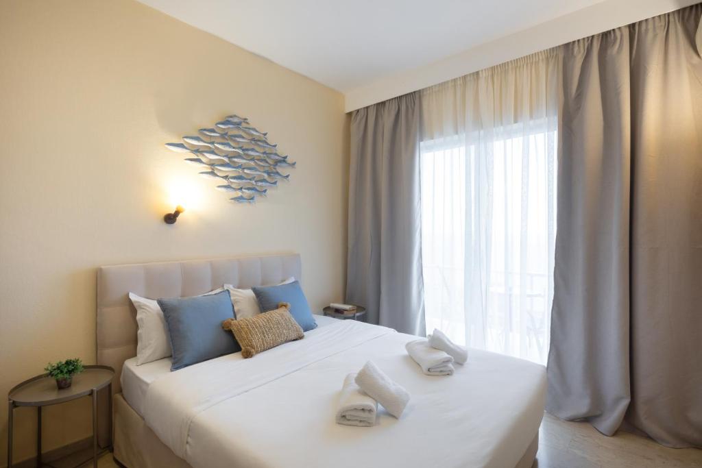 Mūsdienīga guļamistaba ar ērtu gultu, dekoratīvām spilveniem un pievilcīgu sienas dekoru, kas attēlo zivtiņas. Lielas logu aizkari un dabiska gaisma rada patīkamu atmosfēru.