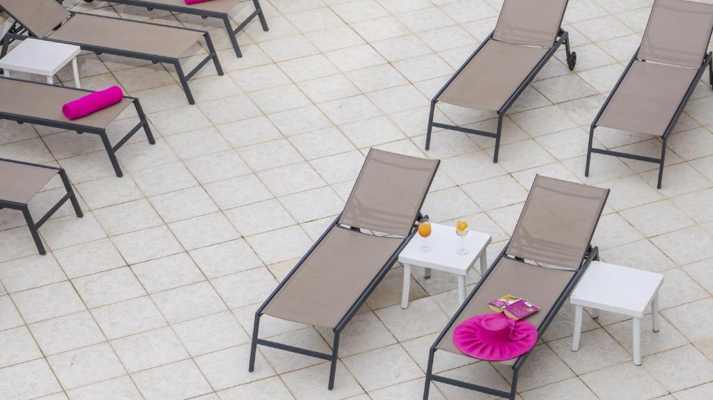 Peldbaseina zona ar saulessargiem un galdiņu, uz kura atrodas dzērieni un grāmata. Pievilcīgas rozā akcenti uz krēsliem piešķir modernu izskatu.