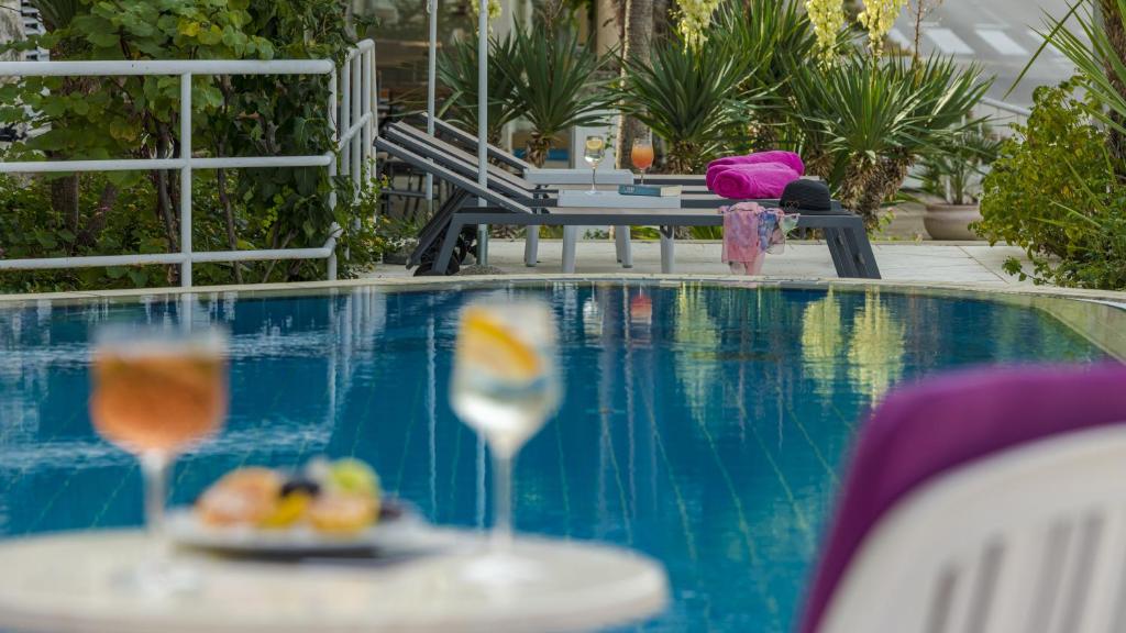 Vasaras atpūtas vieta pie baseina ar kokteiļiem un uzkodām uz galda, apkārt palmām un saulessargiem. Ideāla vieta relaksācijai un izklaidei.