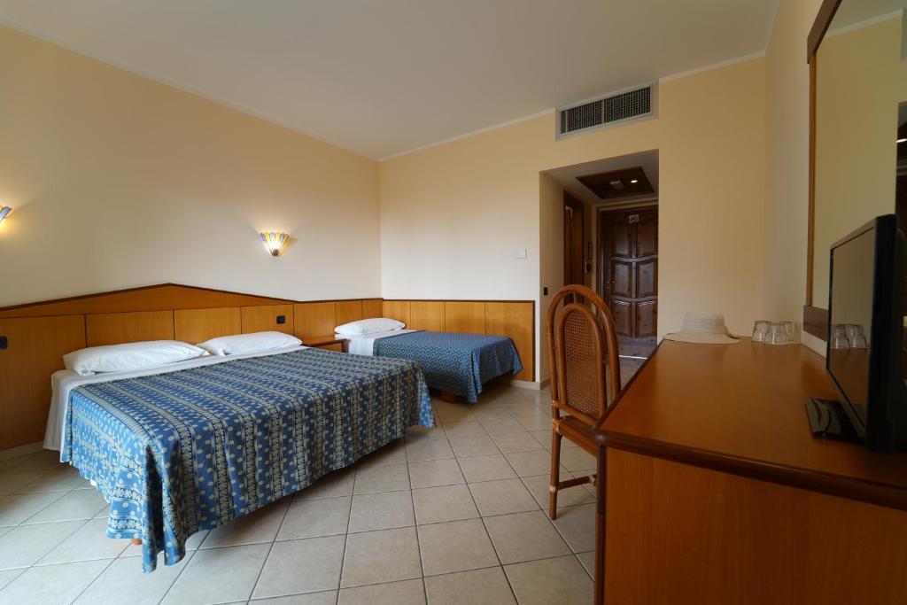 Grezns viesnīcas numurs ar divām gultām, koka mēbelēm un televizoru. Numurā ir gaišas krāsas sienas un flīžu grīda, radot viesmīlīgu atmosfēru.