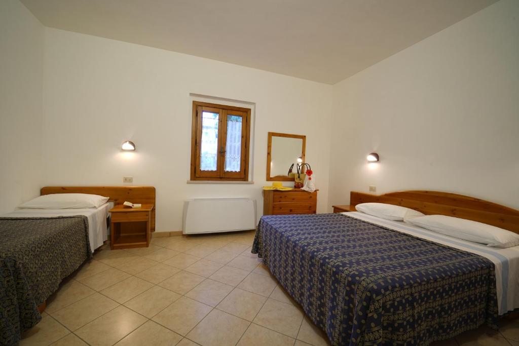 Vienkārša viesnīcas istaba ar divām gultām, koka mēbelēm un logu, caur kuru ieplūst dabiska gaisma. Interjerā dominē gaiši toņi un flīžu grīda.