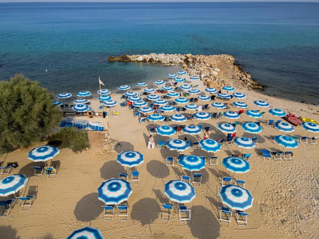 Pludmale ar daudzām saulessargiem un sauļošanās krēsliem, blakus skaidram ūdenim un akmeņu krastam. Ideāla vieta relaksācijai un atpūtai.