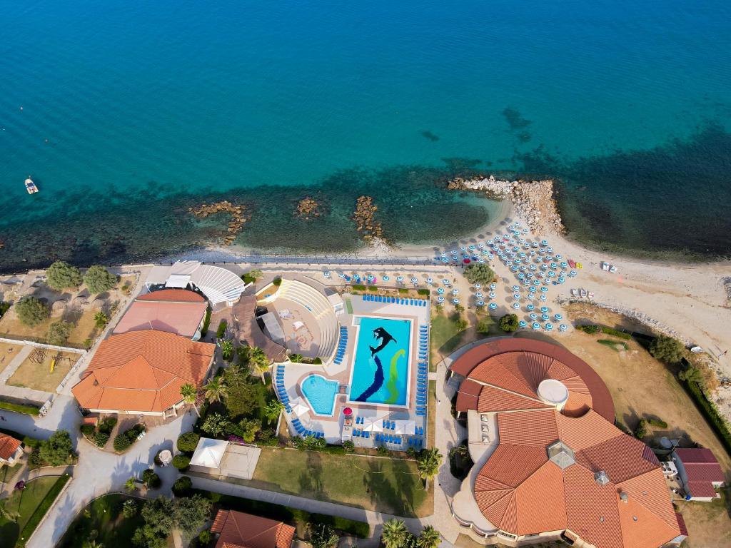 Jūras piekrastes kūrorts ar peldbaseinu un pludmali, kurā ir sauļošanās krēsli. Skats no augšas uz skaisto ūdeni un apkārtējo ainavu.