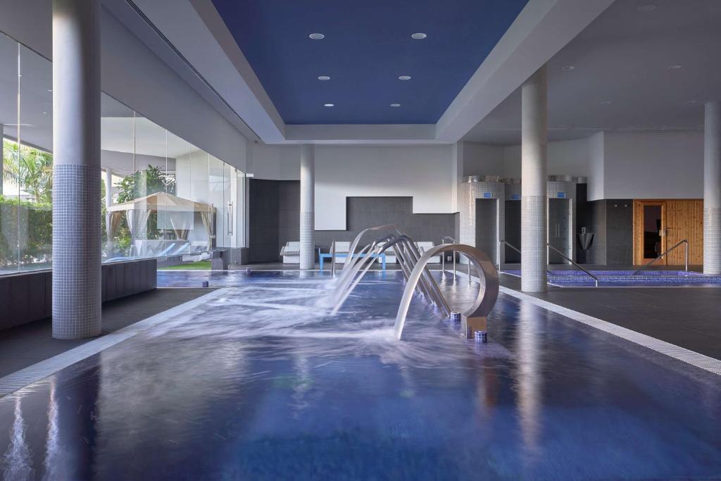 Moderns spa komplekss ar baseinu un relaksācijas zonām, kas nodrošina mierīgu atmosfēru un ūdens procedūras. Gaisma un dizains rada relaksējošu vidi.