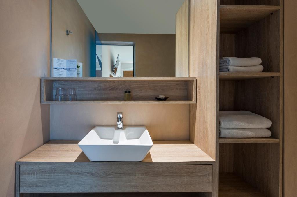 Mūsdienīgs vannas istabas dizains ar koka apdari, izceļot elegantu izlietni un glabāšanas plauktus. Svaigs un minimālistisks interjers rada relaksējošu atmosfēru.