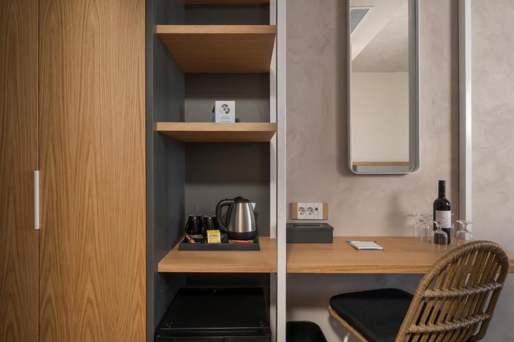 Mūsdienīgas viesnīcas numura interjers ar koka plauktiem, rakstāmgaldu un kafijas komplektu. Redzams spogulis un dzirkstoša vīna pudele uz galda.