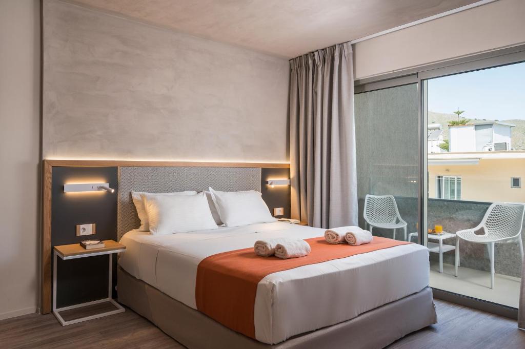 Mūsdienīga viesnīcas numura interjers ar divguļamo gultu, gaišiem toņiem un balkonu. Numurā ir eleganta naktslampiņa un ērti krēsli uz balkona.