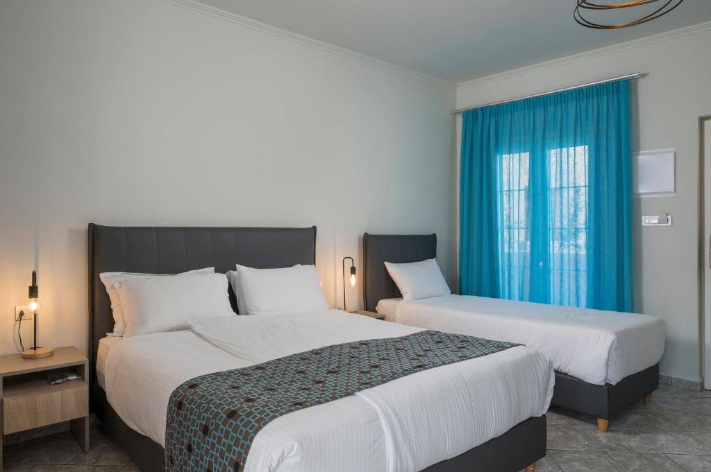 Mūsdienīgs guļamistabas interjers ar divām gultām, gaišām sienām un modernām lampām. Logu aizsedz spilgti zila aizslietne, radot patīkamu atmosfēru.