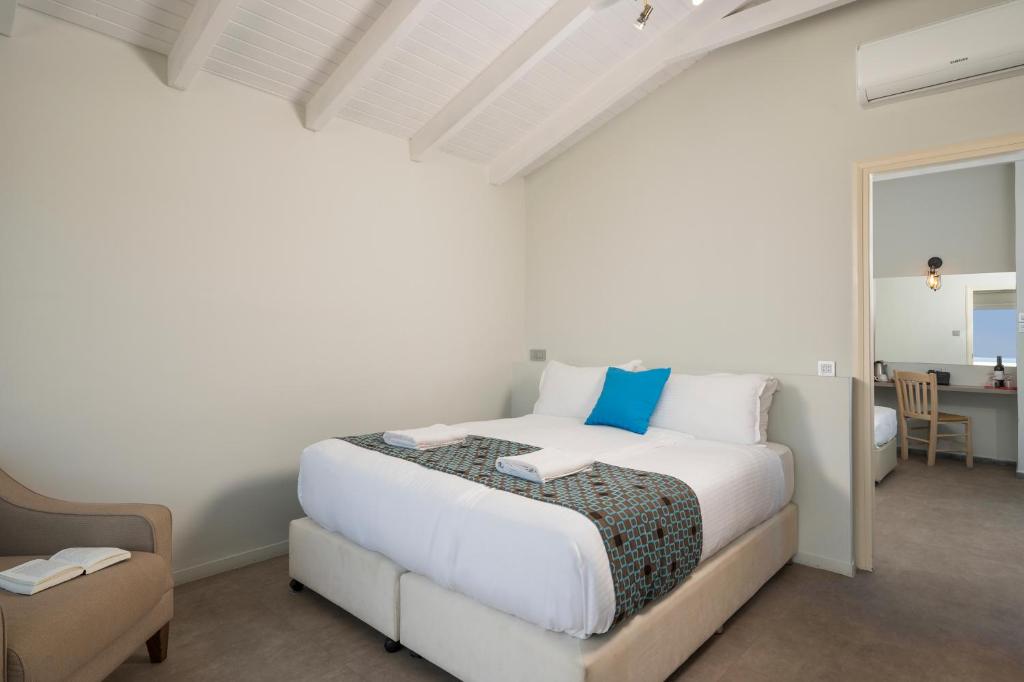 Mūsdienīgs guļamistabas interjers ar plašu gultu, mīkstu krēslu un darba galdu, radot mājīgu un ērtu atmosfēru. Iekārtojums ir gaišs un vienkāršs ar dekoratīvām detaļām.