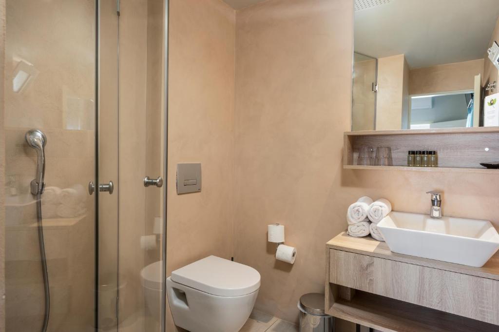 Mūsdienīgs vannas istabas interjers ar dušu, tualeti un dvieļiem uz plaukta. Siltas krāsas un eleganta dizaina elementi veido patīkamu atmosfēru.