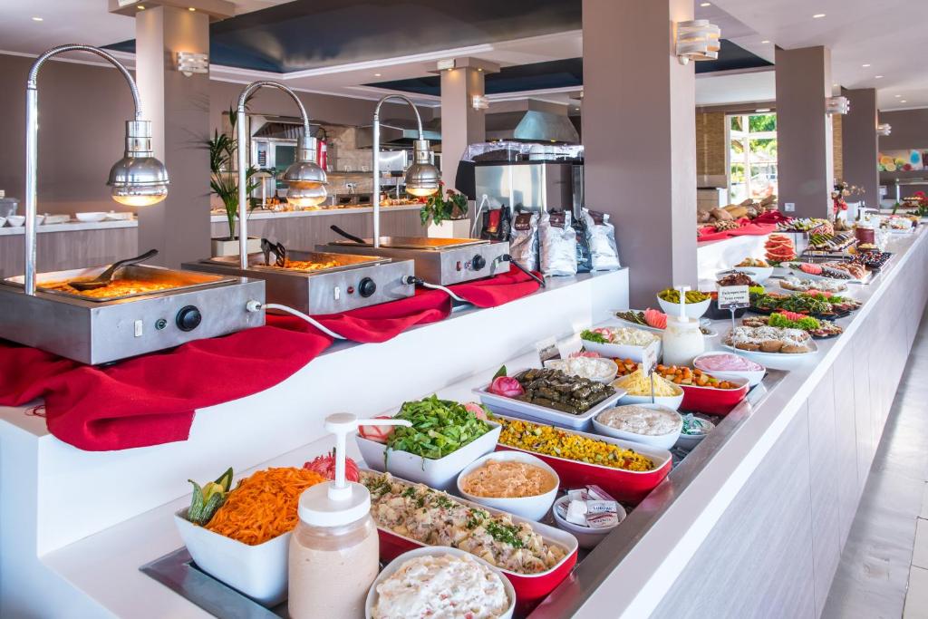 Bagātīgs bufetes galds ar dažādām ēdienu izvēlēm, ieskaitot siltus un aukstus ēdienus, salātus un uzkodas. Galds ir eleganti noformēts un piedāvā plašu izvēli gardumiem.