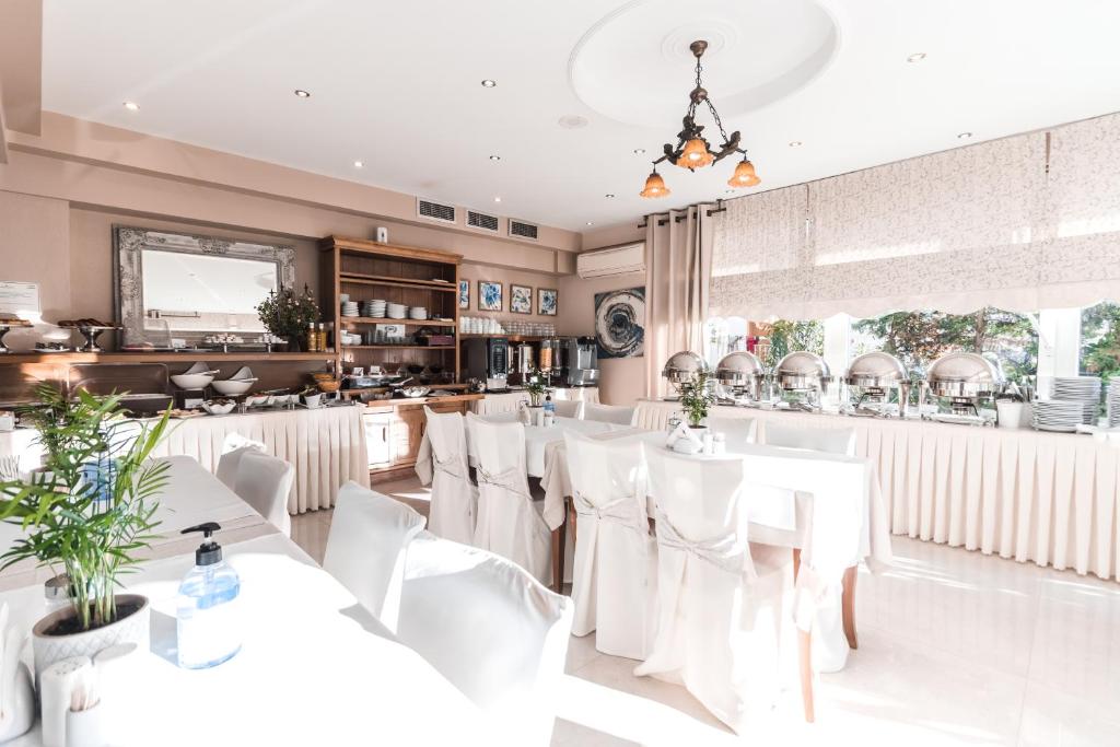 Gaiša un mūsdienīga restorāna iekārtojums ar bufetes galdu un elegantām galdautām. Telpā ir plašas logu vitrīnas, kas ļauj ieplūst dabiskai gaismai.