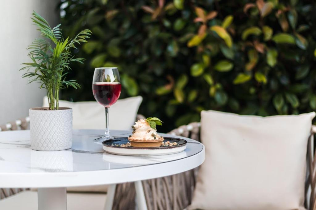Eleganta galda iestatījums ar augu, sarkano vīnu un desertu uz šķīvja. Ideāla atmosfēra relaksējošai brīvdienu atmosfērai.