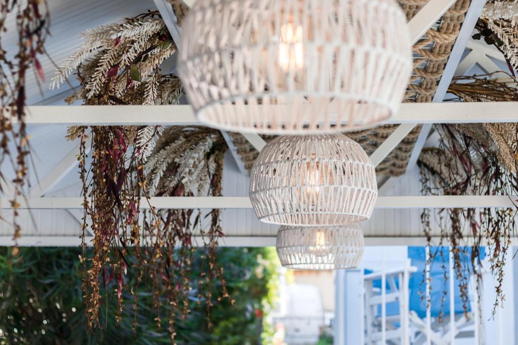 Moderni baltie lampu piekari ar dabu iedvesmotu dekoru, kas rada siltu un viesmīlīgu atmosfēru. Eleganti elementi un augu kompozīcija papildina interjera dizainu.