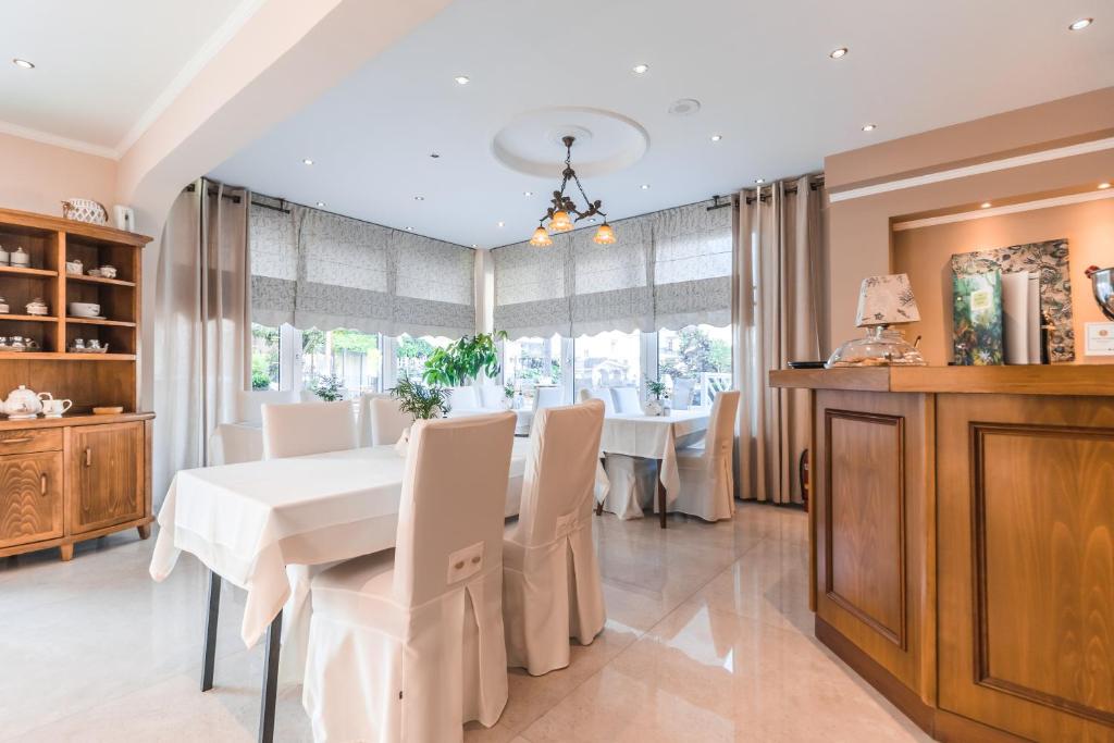 Mūsdienīgs restorāns ar gaišu interjeru, baltām galdautām un elegantām mēbelēm, radot patīkamu atmosfēru. Labi apgaismots ar logiem, kas sniedz skatu uz dārzu.