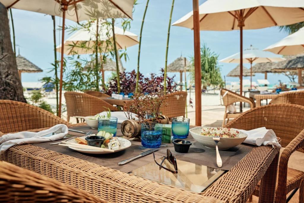 Pludmales restorāns TUI Blue Bahari Zanzibar ar ēdieniem pie galda.