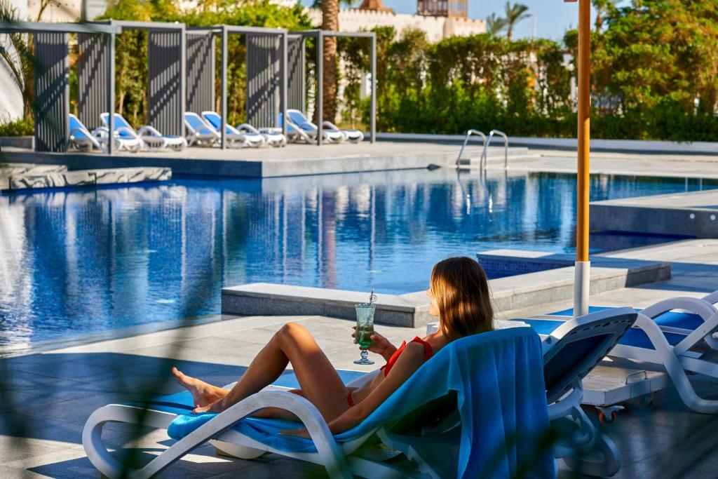 Sieviete relaksējas pie Maritim Jolie Ville Resort & Casino baseina ar kokteili.