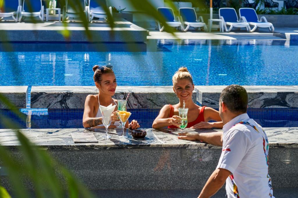 Divas sievietes, kas izbauda kokteiļus pie baseina Maritim Jolie Ville Resort & Casino.