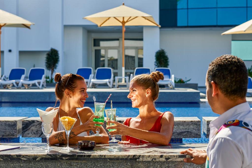 Divas draudzenes baudot kokteiļus pie Maritim Jolie Ville Resort & Casino baseina.