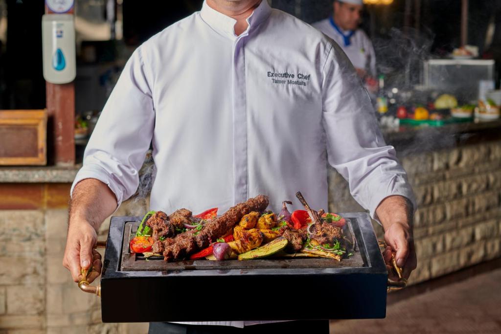 Šefpavārs nes karstu grilu ar gaļu un dārzeņiem Maritim Jolie Ville Resort & Casino