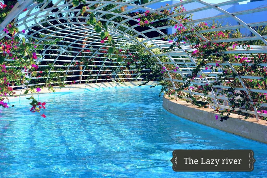 Peldbaseins ar mierīgu ūdeni un ziedošām puķēm, kas rotā balto struktūru, kas veido ainavisku arku. Ideāla vieta relaksācijai un atpūtai.